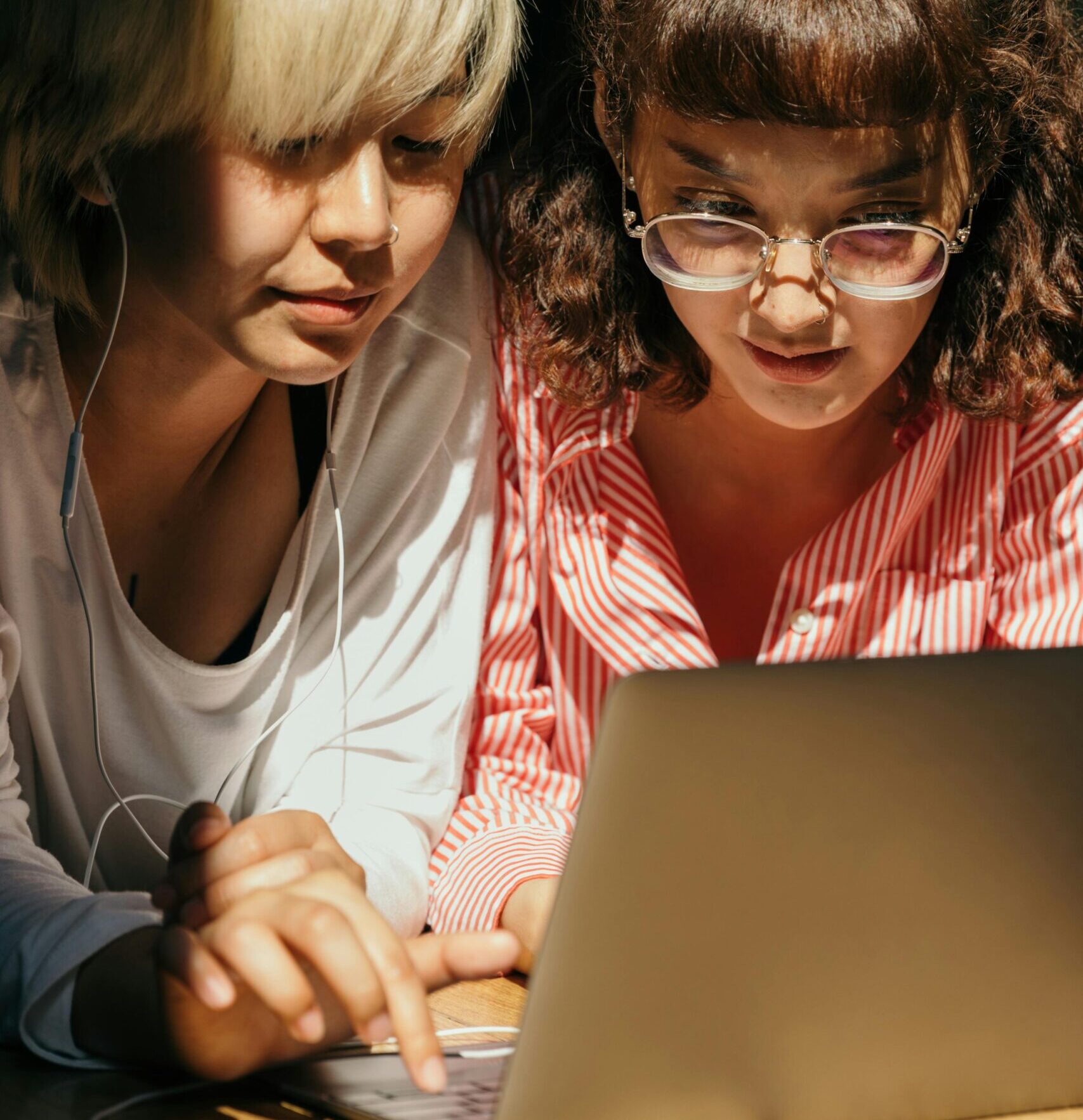 Two young women enjoying leisure time together using a laptop indoors.